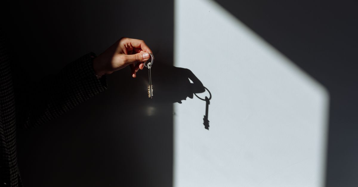 Minimalist photo of a hand holding a key casting a shadow, signifying property ownership